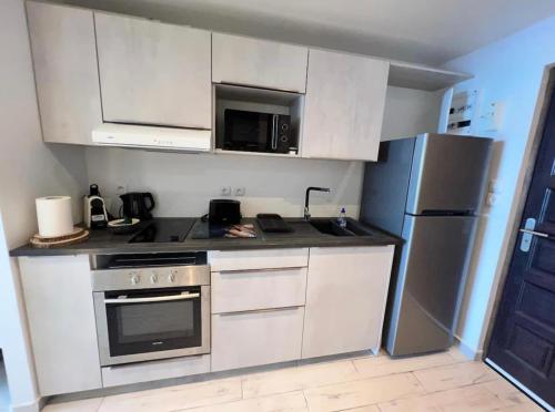 una cucina con armadietti bianchi, piano cottura e frigorifero di Studio Epoustouflant Vue Mer St Martin a Cul de Sac