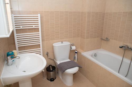 a bathroom with a toilet and a sink and a tub at Οροφομεζονέτα σε συγκρότημα κατοικιών-Μοναδική θέα in Poligiros