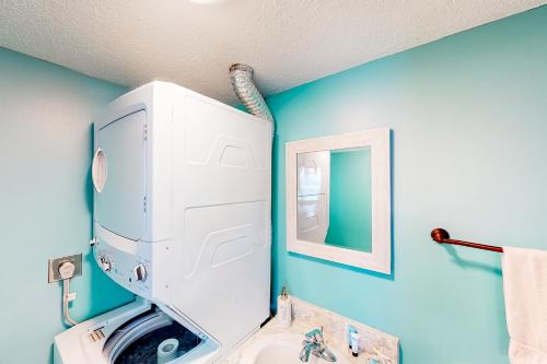 a bathroom with a washing machine and a blue wall at Pinnacle Port A-516 in Panama City Beach