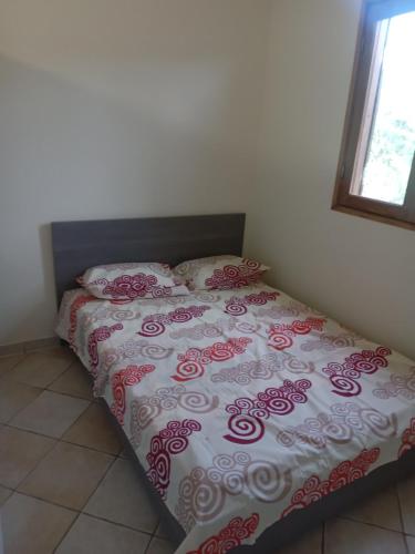 a bed with a red and white comforter in a bedroom at Maison zebre in Port-Louis