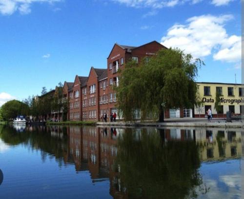 a building next to a river with reflections in the water at Cosy Cottage in the City in Dublin