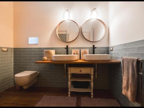 a bathroom with two sinks and two mirrors at Villa Platani Luxury Suite in Cianciana