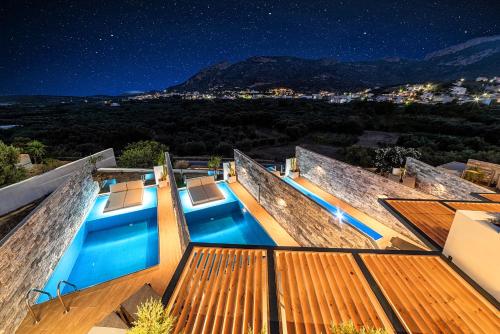 a villa with a swimming pool at night at Aelia Suites in Agios Nikolaos