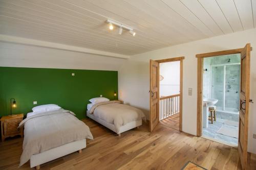 2 camas en una habitación con una pared verde en Au cœur des champs - Gîte, en Nivelles
