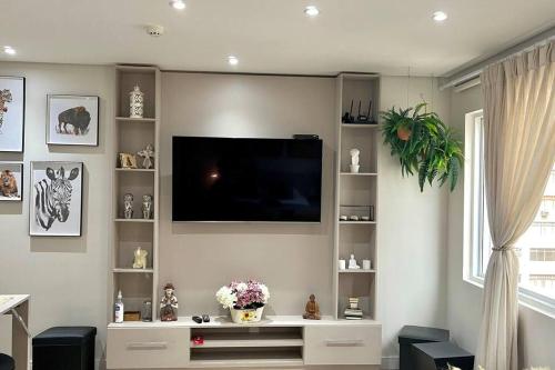 sala de estar con TV de pantalla plana en la pared en 904 - Flat Studio Consolação Premium Elegance, en São Paulo