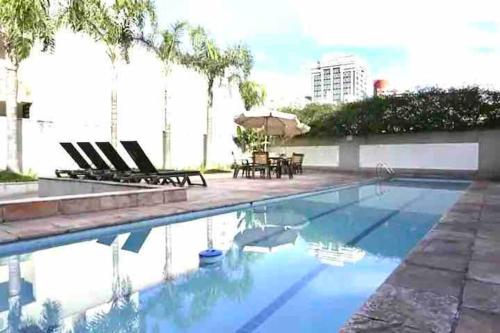 una piscina con sillas y sombrilla en 904 - Flat Studio Consolação Premium Elegance, en São Paulo