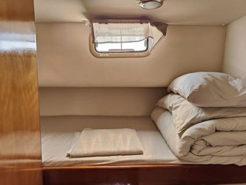 Bett in einem kleinen Zimmer mit Fenster in der Unterkunft Huifeng Chen in Lissabon