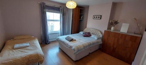 um quarto com uma cama, uma mesa e uma janela em Nice 3 Bedroom House Ealing em Londres