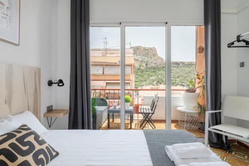1 dormitorio con cama y vistas a un balcón en CASA MILA SV19 guesthouse, en Alicante