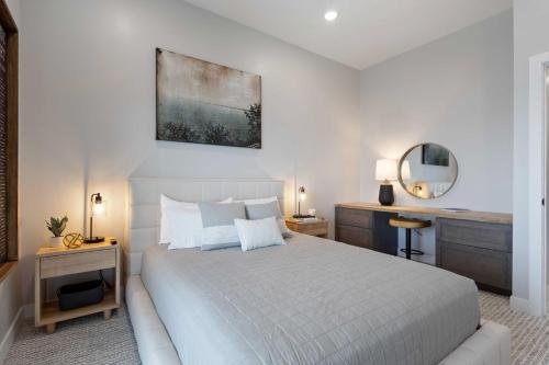 Dormitorio blanco con cama blanca y espejo en Luxury Lakefront Condo with Private Hot Tub and Sauna, en Watertown