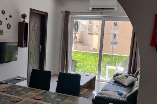 une salle à manger avec une table, des chaises et une fenêtre dans l'établissement Sunny Day Flat, à San Pawl il-Baħar