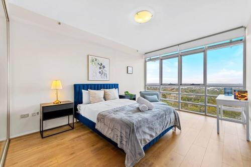 a bedroom with a bed and a desk and windows at Stunning City and Water View Apartment in Sydney
