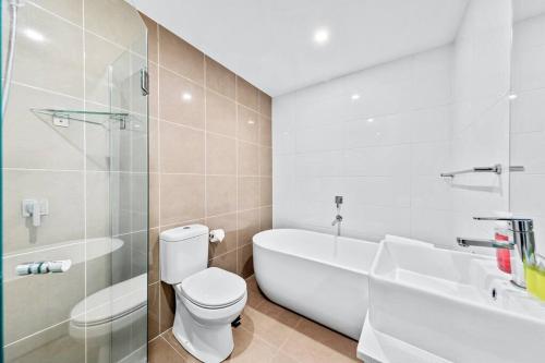 a bathroom with a toilet and a tub and a sink at Stunning City and Water View Apartment in Sydney