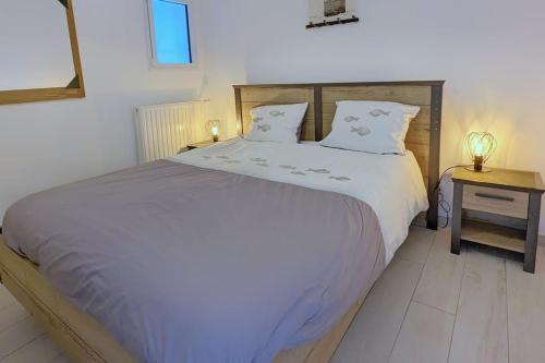 une chambre avec un grand lit blanc avec deux oreillers dans l'établissement Appartement pour 3 personnes Sur la plage Les pieds dans leau, à Plonévez-Porzay