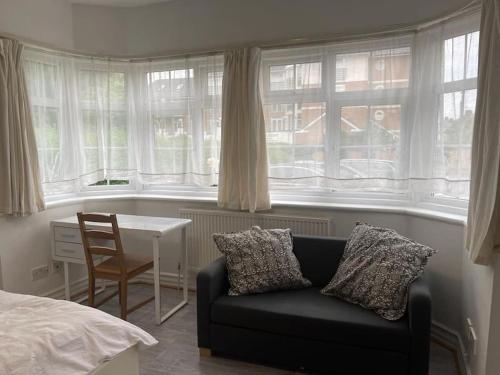 een woonkamer met een bank, een tafel en ramen bij New Studio on Golders Green RD in Londen