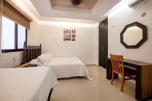 a bedroom with two beds and a desk and a mirror at Family Vacations apartment Ocean View in Cancún