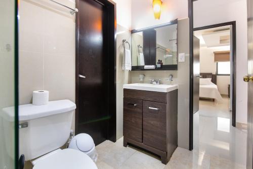 a bathroom with a toilet and a sink and a mirror at Family Vacations apartment Ocean View in Cancún