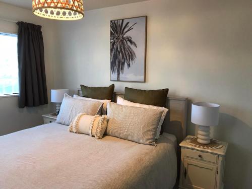 a bedroom with a bed with pillows and a chandelier at Vicroad The Mount in Mount Maunganui