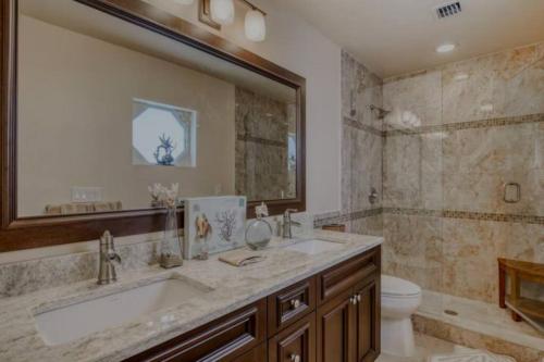 a bathroom with a sink and a toilet and a mirror at Salty Slumber Relaxing 2 bedroom 2 bath Get Away in the Lower Keys in Summerland Key