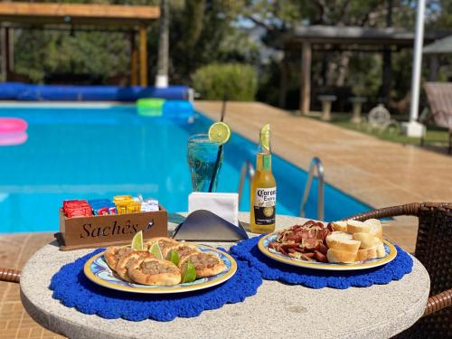 a table with two plates of food and a bottle of beer at Pousada Mirante das Estancias in Águas de Lindóia