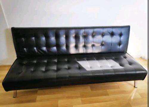 a black leather couch sitting on a wooden floor at ¶Pet Friendly Cosy Quite Room+TV+Sofa in Glenfield