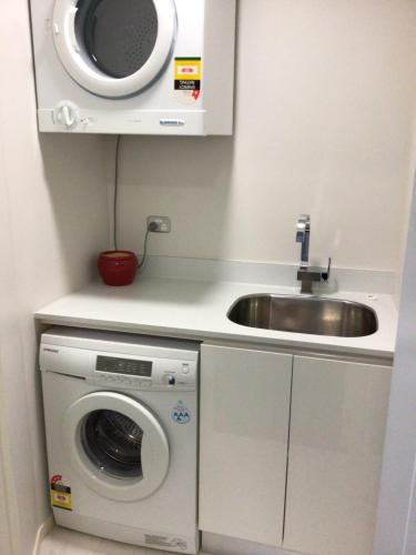 a kitchen with a sink and a washing machine at Beachside studio in New Plymouth