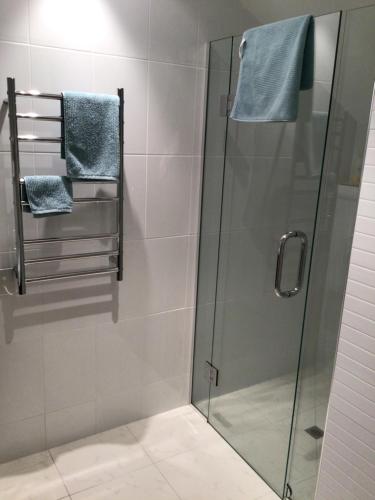a shower with a glass door and towel racks at Beachside studio in New Plymouth