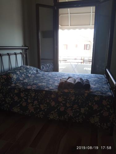 una cama con zapatos en ella con una ventana en Ante Portum, en Nafpaktos