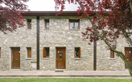 - un bâtiment en pierre avec des portes et des fenêtres marron dans l'établissement Casa los Altos de Santiago, à Villanúa