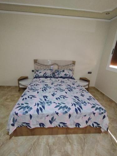 een slaapkamer met een bed met een blauwe en witte sprei bij appartement joliment meublé pour 4/5 personnes à Imzouren 