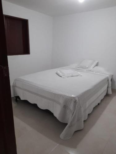 ein weißes Bett in einem weißen Zimmer mit einem TV in der Unterkunft Apartamento la 20 in Pereira