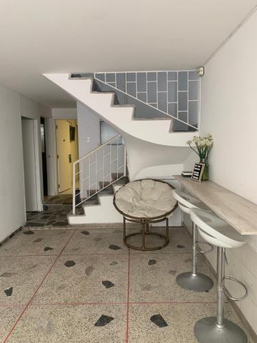 a room with a staircase and a table and stool at Hotel Quintas de Normandia in Bogotá