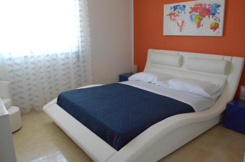 a white bed in a room with an orange wall at Campagne Iblee in Ragusa