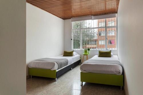 2 camas en una habitación con ventana en Hotel Quintas de Normandia, en Bogotá
