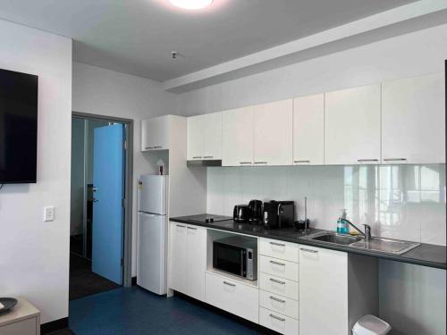 uma cozinha com armários brancos, um lavatório e um frigorífico em 2BR entire apt City central em Adelaide