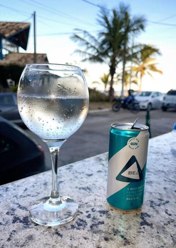 a glass of wine sitting on a table next to a can at Felicidade in sea front in Saquarema