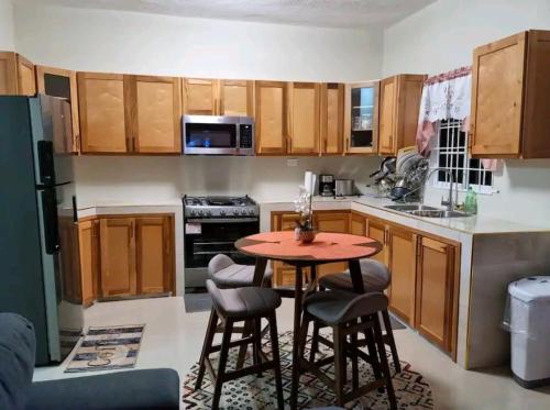 a kitchen with wooden cabinets and a table and chairs at S.G Apartment Complex. in Linstead