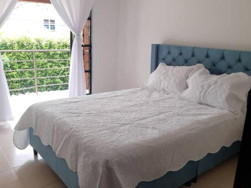 uma cama azul num quarto com uma janela em Quintas de las Acacias Villavicencio em Villavicencio