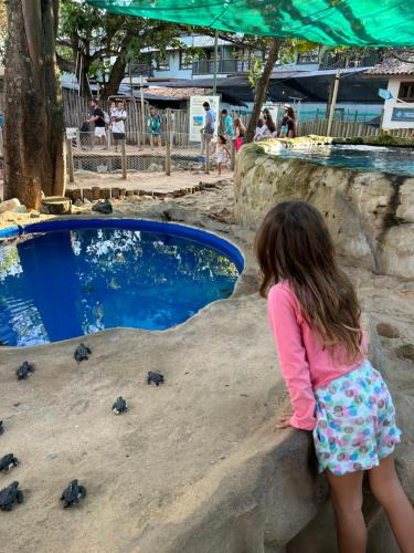 a little girl standing on a rock looking at turtles at Pousada Bar Café Algas Marinhas in Praia do Forte