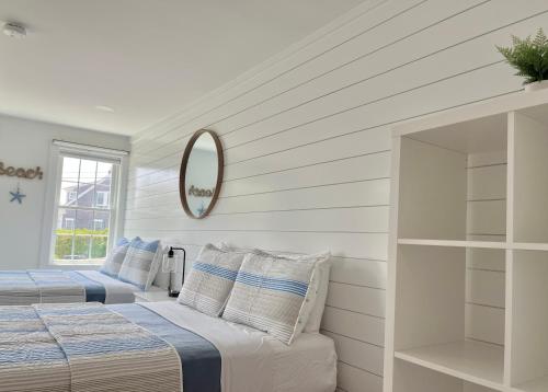 two beds in a white room with a mirror at Kingfisher Harwich Port in Harwich Port