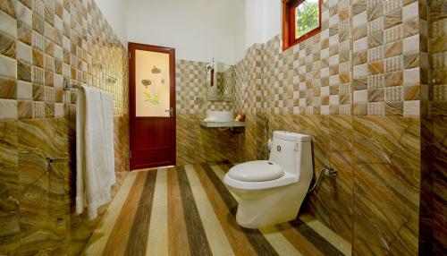 a bathroom with a toilet and a red door at Kamal Villa in Ahungalla