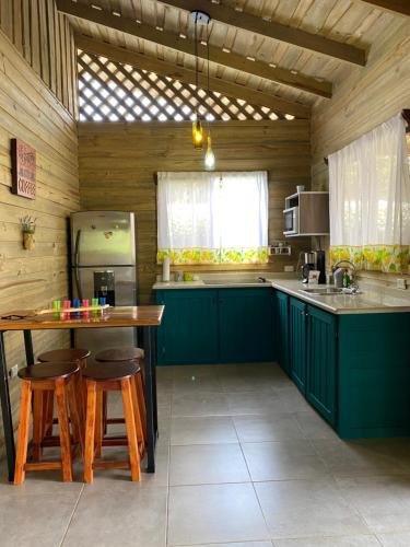 a kitchen with green cabinets and a table and stools at Cabaña ValFio Bahía Ballena in Uvita
