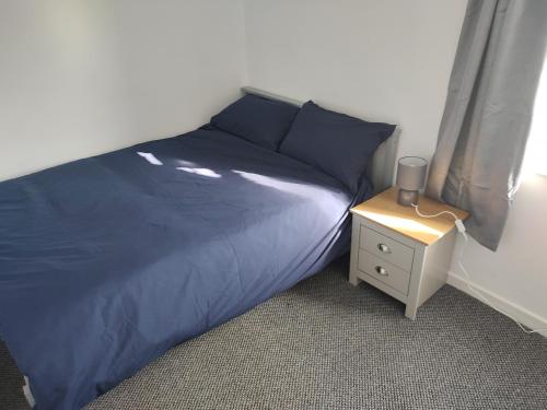 a bedroom with a blue bed and a night stand at Leicester Street in Burton upon Trent