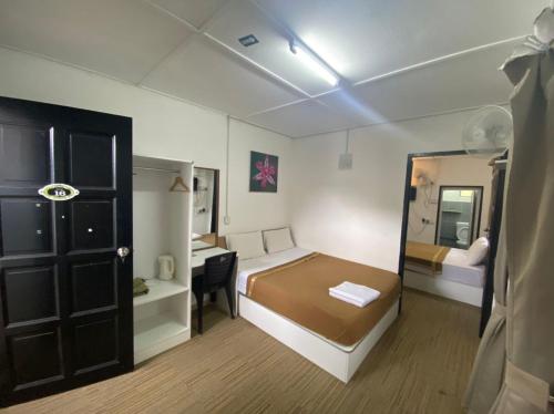 Habitación pequeña con cama, escritorio y espejo. en Darulmakmur Chalet en Cameron Highlands