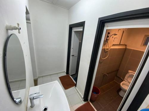 een badkamer met een wastafel, een toilet en een spiegel bij Darulmakmur Chalet in Cameron Highlands