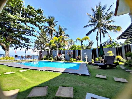 a backyard with a swimming pool and grass at Baki Divers and Beach Resort in Dauin