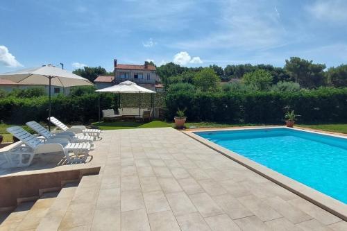 a swimming pool with chairs and umbrellas in a yard at Family-friendly apartments with swimming pool Pomer, Medulin - 17681 in Pula