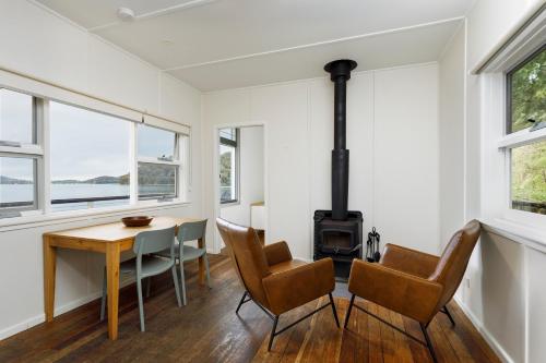 a room with a table and chairs and a wood stove at Currawong Beach Cottages in Great Mackerel Beach