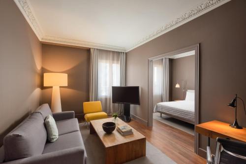 ein Wohnzimmer mit einem Sofa, einem Bett und einem Spiegel in der Unterkunft Le Meridien Barcelona in Barcelona