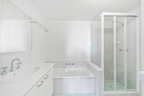 a white bathroom with a sink and a shower at Bay Lodge - Private Apartments in Gold Coast